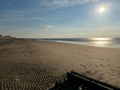 a sandy beach with a pier in the distance at Pebble Stones in Hunstanton