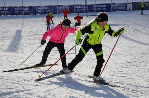 two children are skiing down a snow covered slope at Apartment Österreich in Ramsau am Dachstein