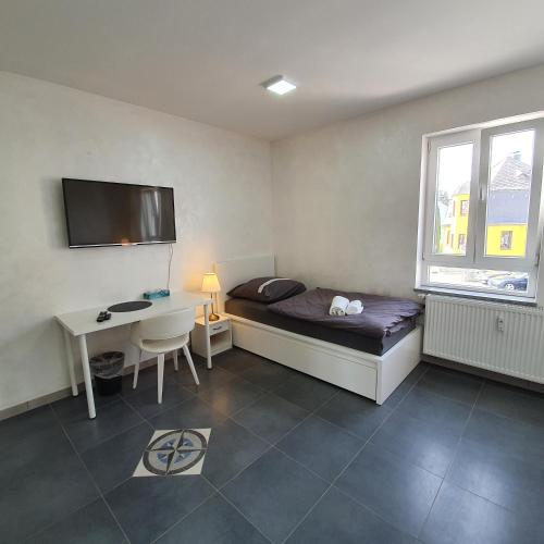 una camera da letto con un letto, una scrivania e una TV di Pension Bad Soden / Apartment and Rooms a Bad Soden am Taunus