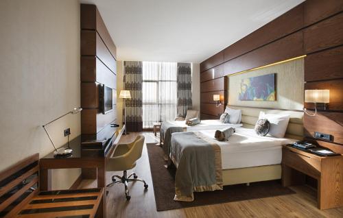 a hotel room with two beds and a desk at Dedeman Erbil Hotel City Center in Erbil