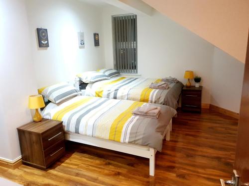 a bedroom with two beds and a staircase at Homebird Property - Conway House in Leeds