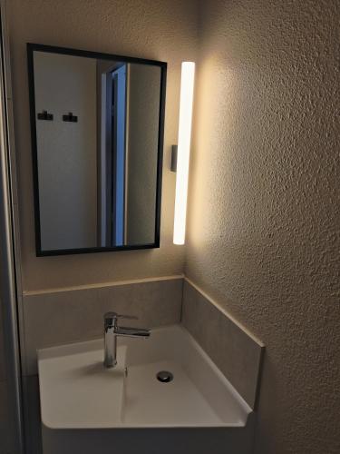 une salle de bain avec un lavabo et un miroir dans l'établissement B&B HOTEL La Rochelle Centre Les Minimes, à La Rochelle