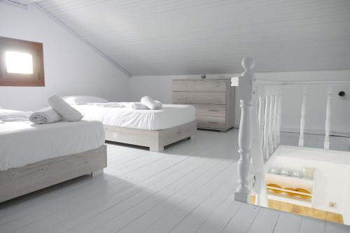 a white bedroom with two beds and a dresser at Jasmine apartments in Pythagoreio