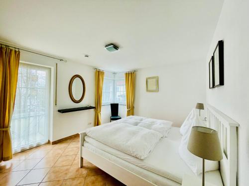 een witte slaapkamer met een bed en een raam bij Birkenhof-Birke in Bad Wörishofen