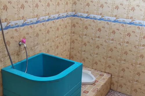 ein Badezimmer mit einer blauen Badewanne neben einem WC in der Unterkunft Oma Homestay Pagar Alam Syariah RedPartner in Pagaralam
