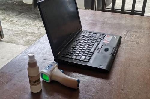 a laptop computer sitting on a table with a bottle of glue at Oma Homestay Pagar Alam Syariah RedPartner in Pagaralam