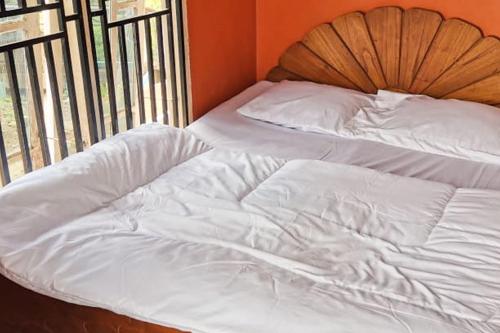 Bett mit weißer Bettwäsche und einem Kopfteil aus Holz in der Unterkunft Oma Homestay Pagar Alam Syariah RedPartner in Pagaralam