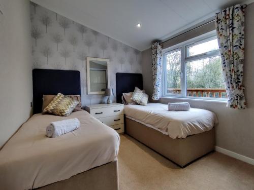 モルトンにあるDeneb Lodge with Hot Tubのベッド2台と窓のある寝室