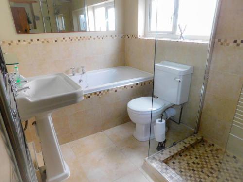 a bathroom with a tub and a toilet and a sink at Riverdale Cottage in Rhuddlan