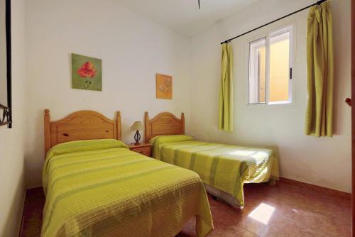 two beds in a room with yellow sheets and a window at Casa El Cardon B2 in Buenavista del Norte