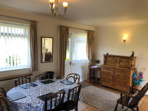 a dining room with a table and chairs and windows at Derwent View in Bamford