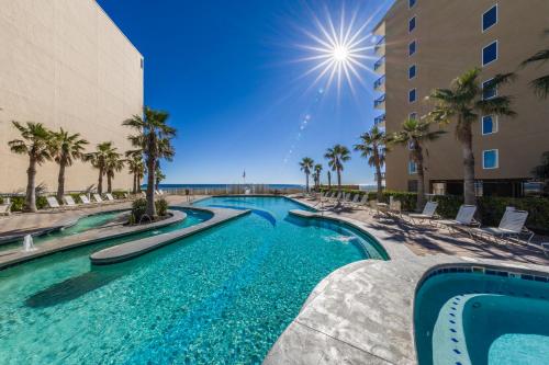 a swimming pool with palm trees and a building at Crystal Tower 1506 in Gulf Shores