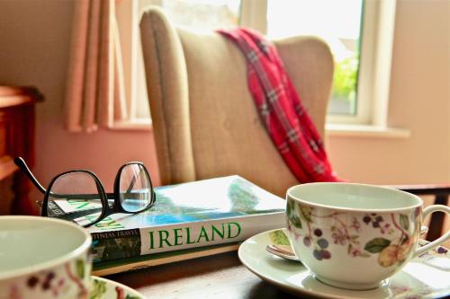 un libro sentado en una mesa con dos tazas de café en Fough East, Oughterard, en Oughterard