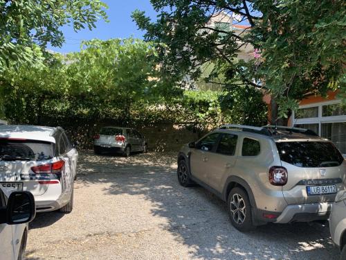 two cars parked in a parking lot next to a house at Apartments Lea in Orebić