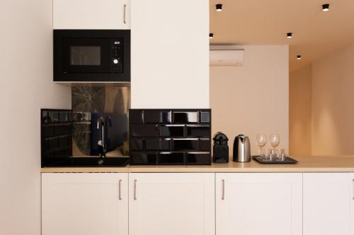 a kitchen with white cabinets and a black microwave at Welldone Sierpes Boutique in Seville