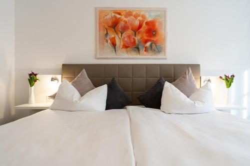 1 cama con almohadas blancas y una pintura en la pared en Hotel La Fleur en Überlingen