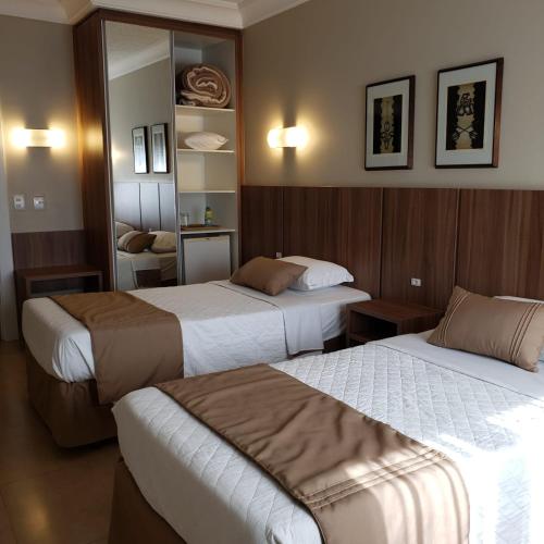 a hotel room with two beds and a mirror at Hotel Alvorada in Concordia