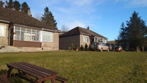 a wooden bench in a yard next to a house at Scotland Shooting Club Kirriemuir in Kirriemuir