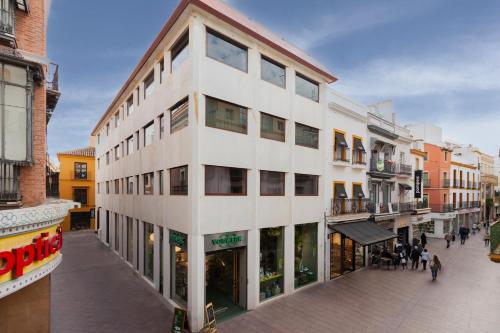 um edifício branco alto numa rua da cidade em Welldone Sierpes Boutique em Sevilha
