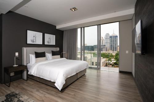 1 dormitorio con cama grande y ventana grande en The Capital Empire, en Johannesburgo