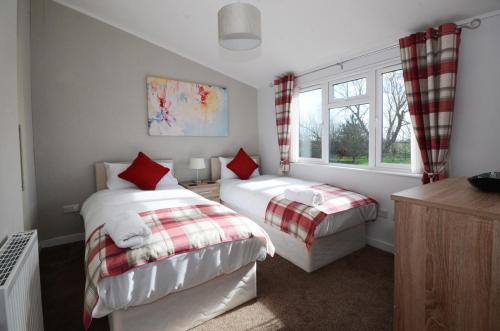 1 Schlafzimmer mit 2 Betten und einem Fenster in der Unterkunft Ryedale Lodge with Hot Tub in Malton
