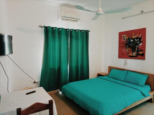 1 dormitorio con cama verde y cortina verde en Le Hublot en Cotonú