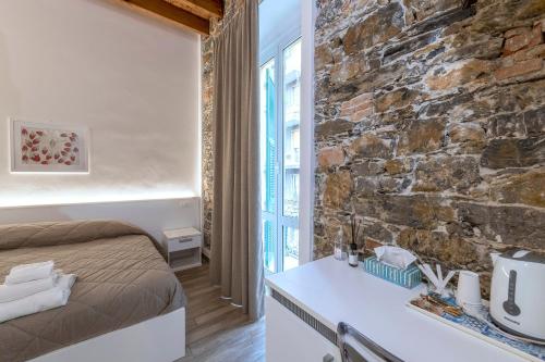 una camera da letto con un muro in pietra, un letto e un tavolo di La casa di Mattia a La Spezia
