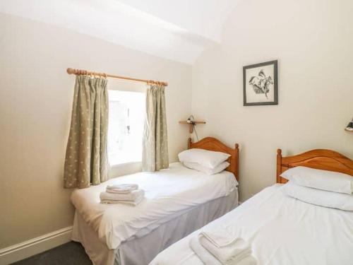 two twin beds in a room with a window at Wetton Barns Holiday Cottages in Ashbourne