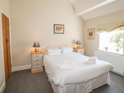 a bedroom with a large white bed and a window at Wetton Barns Holiday Cottages in Ashbourne