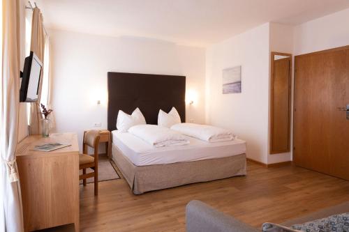 ティローロにあるPension Leimerhofのベッド、デスク、ベッドが備わるホテルルームです。
