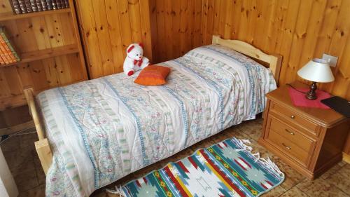a teddy bear sitting on a bed in a bedroom at B & B SENTIERO VALTELLINA in Castello dellʼAcqua