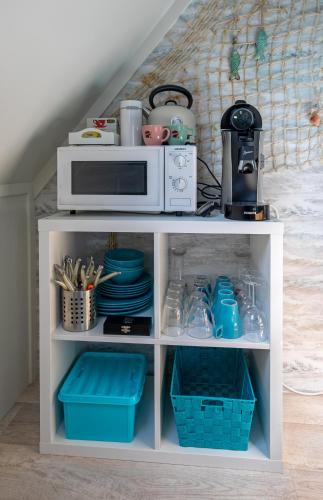 a white cabinet with a microwave and dishes on it at Texels Verzetje in Den Burg