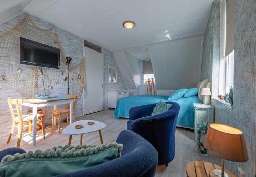 a bedroom with a blue bed and a table and chairs at Texels Verzetje in Den Burg