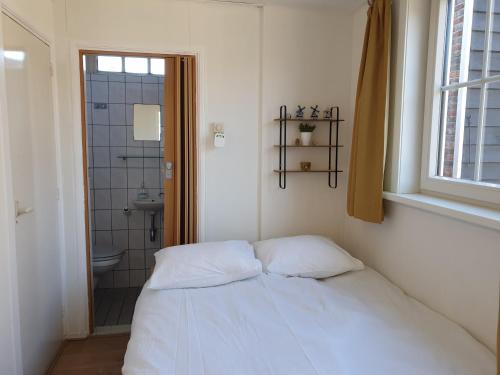 a bedroom with a bed and a bathroom with a shower at Hout 25 in Westkapelle