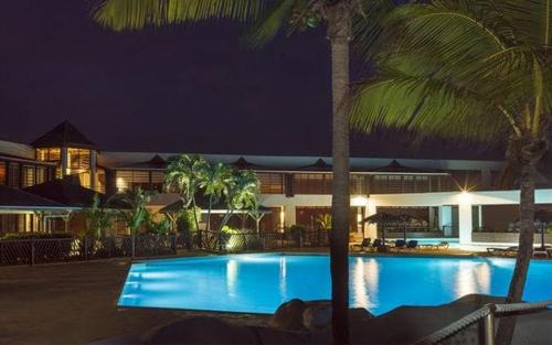 a swimming pool with palm trees in front of a building at Studio 25 m Manganao Joela 4 personnes avec machine a laver in Saint-François