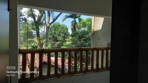 a window with a view of a palm tree at Shivaji Inn Kaziranga in Kāziranga