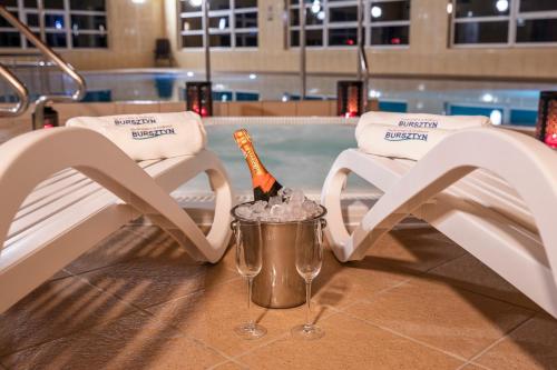 a bottle of champagne in a bucket next to two chairs at BURSZTYN - BERNSTEIN APARTMENTS in Dąbki