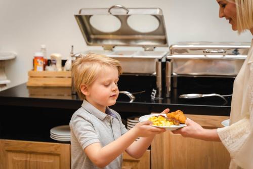 a woman handing a boy a plate of food at Hotel du Théâtre in Bruges