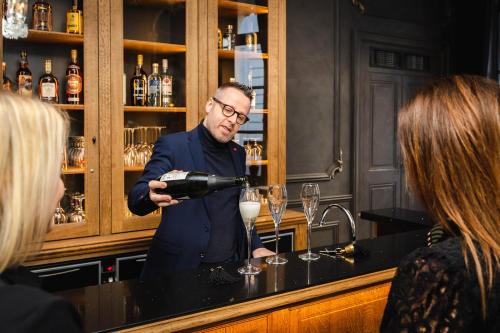 un homme versant du vin dans un verre au bar dans l'établissement Hotel du Théâtre, à Bruges