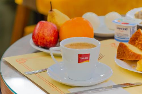 a cup of coffee on a table with apples and bread at Hotel Duas Nações in Lisbon
