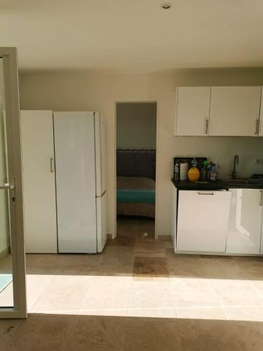 une cuisine avec des placards blancs et une chambre avec un lit dans l'établissement Appartement chaleureux à Cavalaire-sur-Mer 40 m² avec terrasse, à Cavalaire-sur-Mer