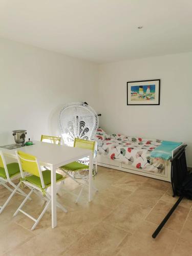 une pièce avec une table, des chaises et un lit dans l'établissement Appartement chaleureux à Cavalaire-sur-Mer 40 m² avec terrasse, à Cavalaire-sur-Mer