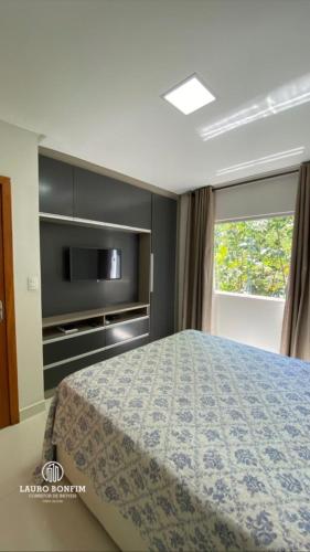 a bedroom with a bed and a tv and a window at Residencial Rocha - Praia de Guaratiba - Prado - Ba in Prado