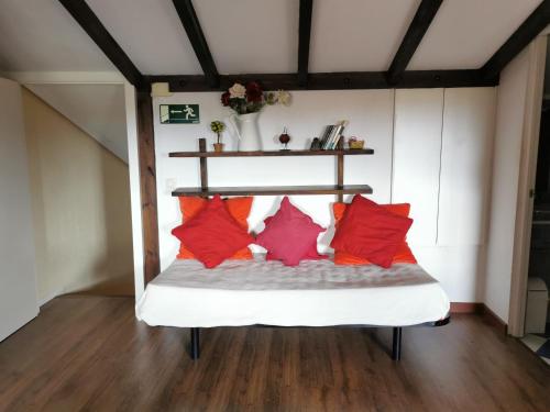 a bed in a room with red pillows on it at La Cerca de Torrecaballeros, a 10 min de Segovia in Torrecaballeros