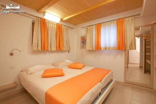 1 Schlafzimmer mit 2 Betten und orangefarbenen Kissen in der Unterkunft Appartamenti Green esclusivo riservato soleggiato in Livigno