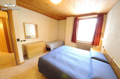 sypialnia z niebieskim łóżkiem i oknem w obiekcie Appartamento MilHouse by Livigno Accomodation w Livigno