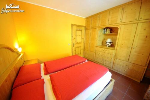 a bedroom with a bed with red sheets and wooden cabinets at Casa Florin Giumel con vista sulle piste da sci in Livigno