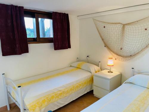 Un dormitorio con dos camas y una ventana. en Villetta La Risacca, en Costa Paradiso