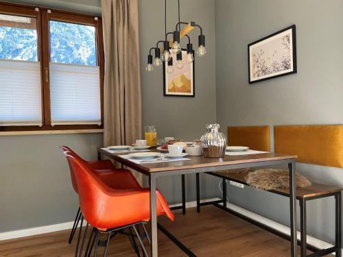 a dining room with a table and orange chairs at Das Bergquartier - Ferienwohnung Zugspitze in Oberau