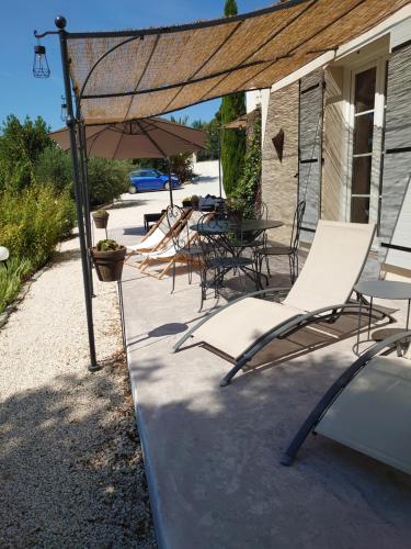 a group of chairs and an umbrella on a patio at B&B La Boissière Et Le Vialat in Montagnac